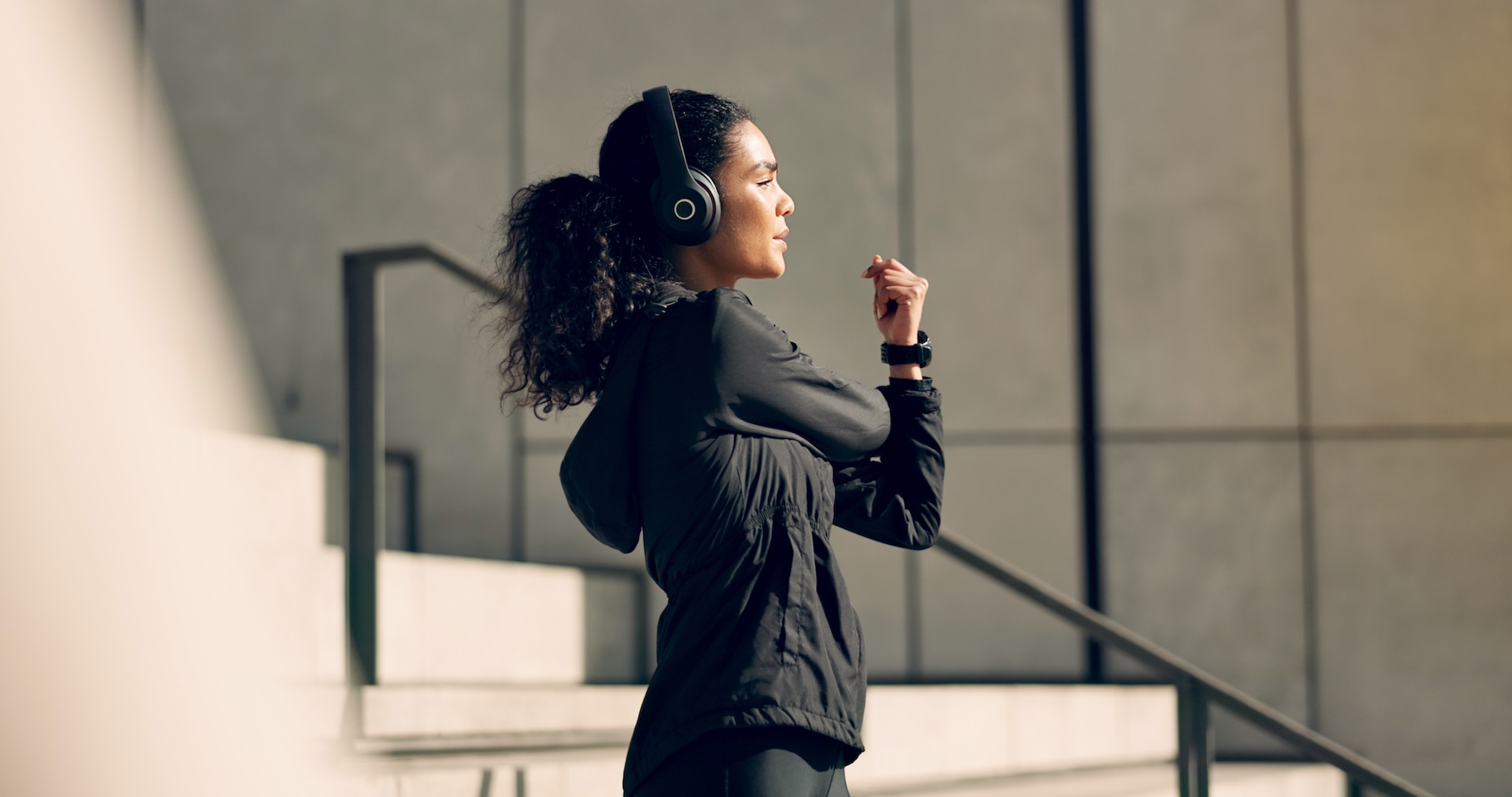 A young woman wearing headphones and stretching her arms